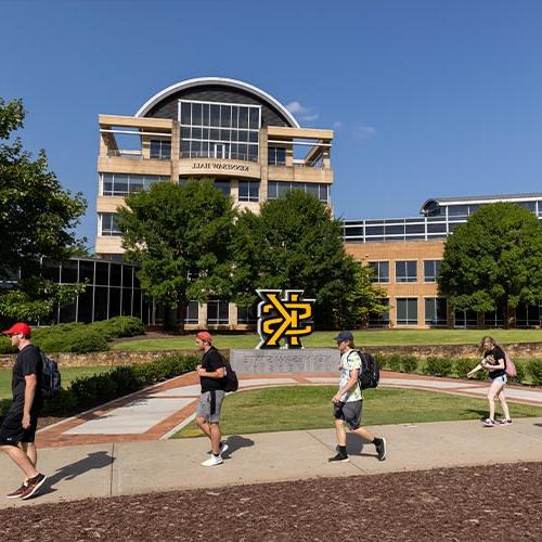 ksu students on kennesaw campus passing kennesaw hall.